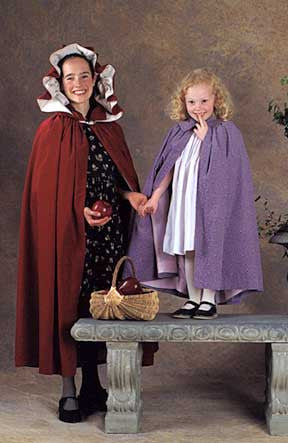 A young women standing holding a red apple and a little girl standing on a stone bench with a basket full of apples both wearing 208 Kinsale Cloak for Young Maidens.